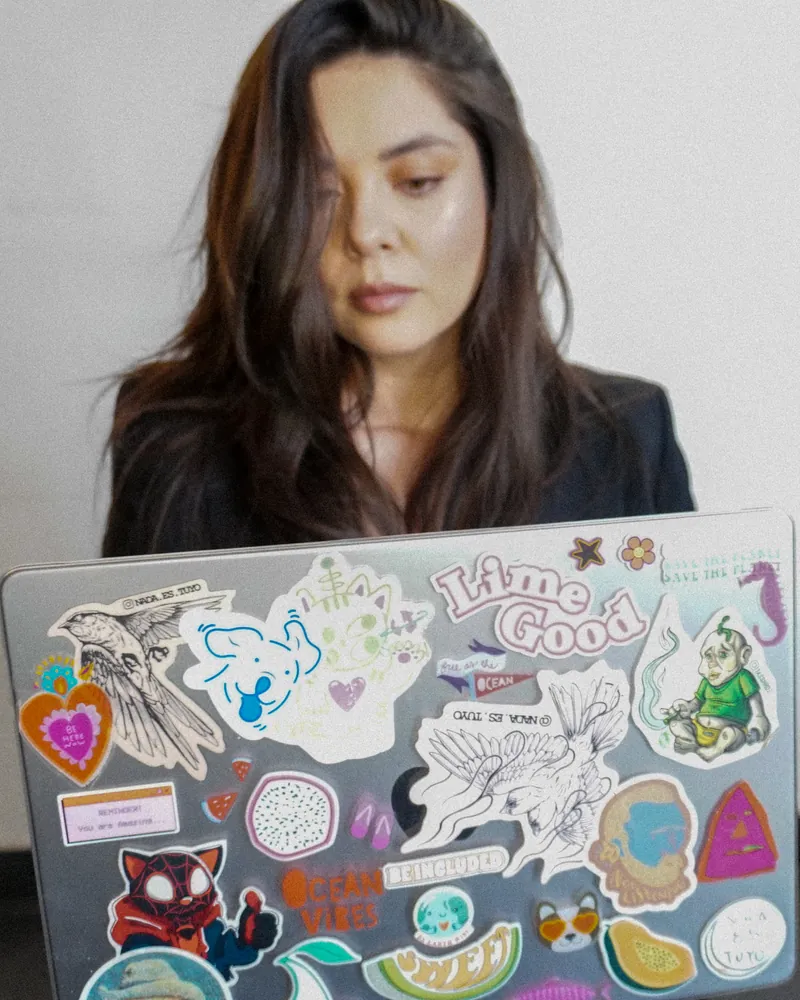 Lucía Ortega trabajando en su laptop, cubierta de stickers.