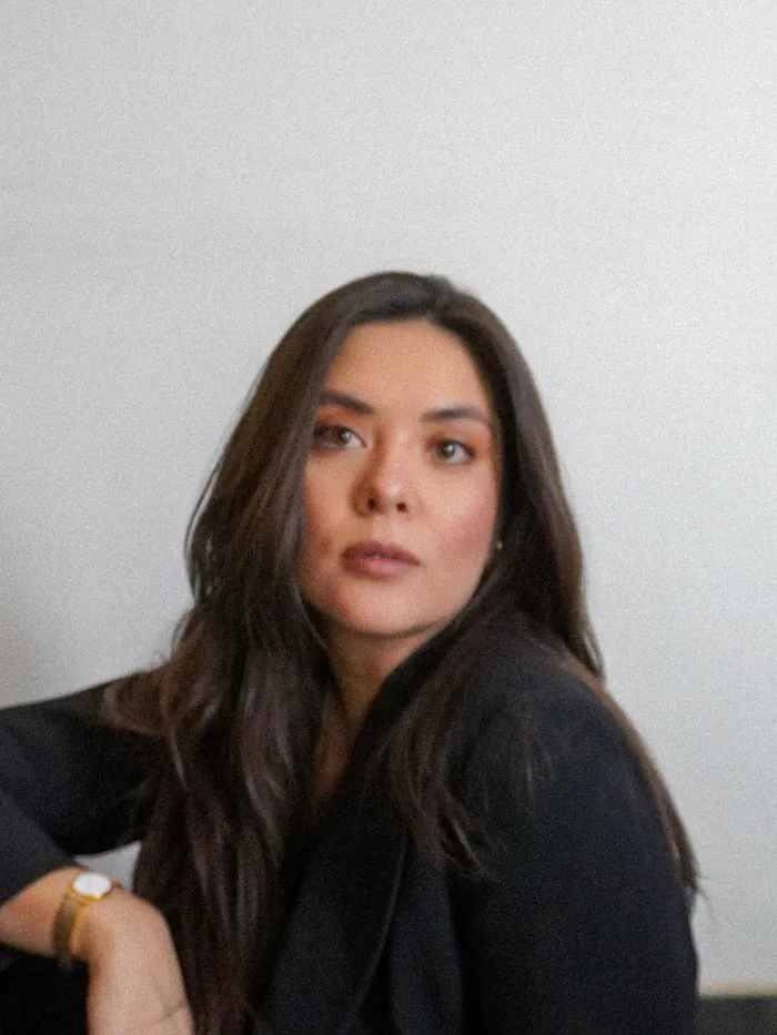 Retrato de Lucía Ortega con chaqueta negra, frente a una pared blanca.