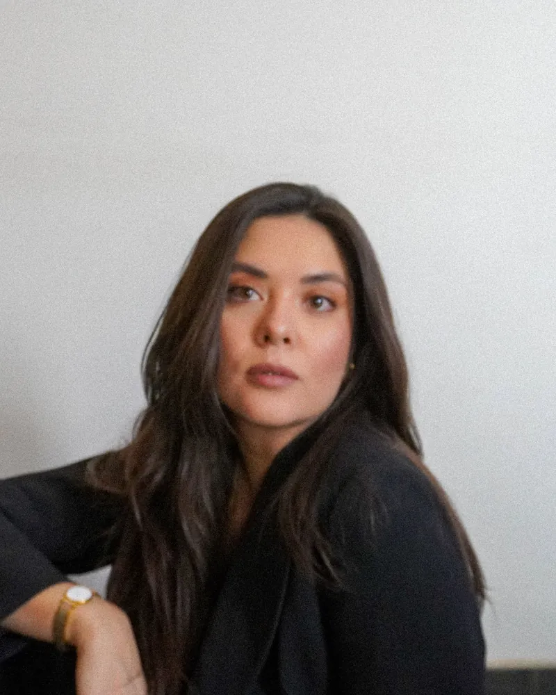 Retrato de Lucía Ortega con chaqueta negra, frente a una pared blanca.
